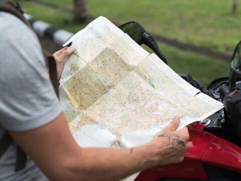 crop man studying city map sitting on motorbike